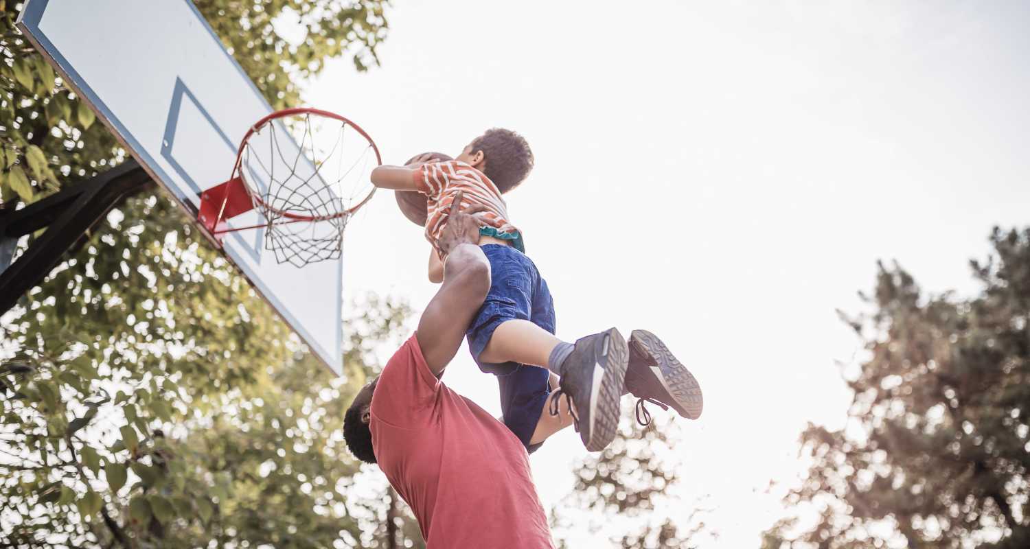 A father helping his child reach the basket in a park near Arbors at Cahaba River in Birmingham, Alabama