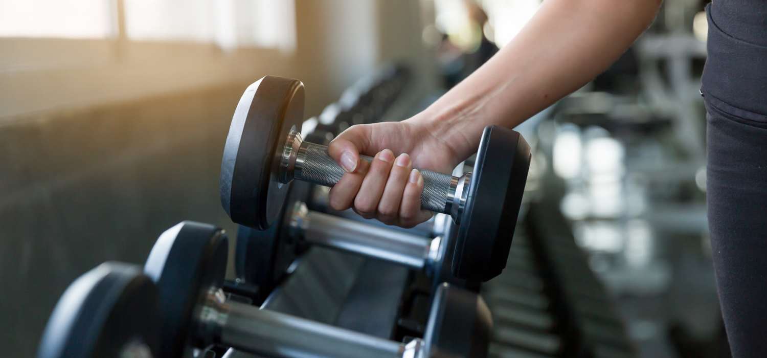 Resident picking up weights in the fitness center at Indian Terrace I Apartments in Auburn, Indiana