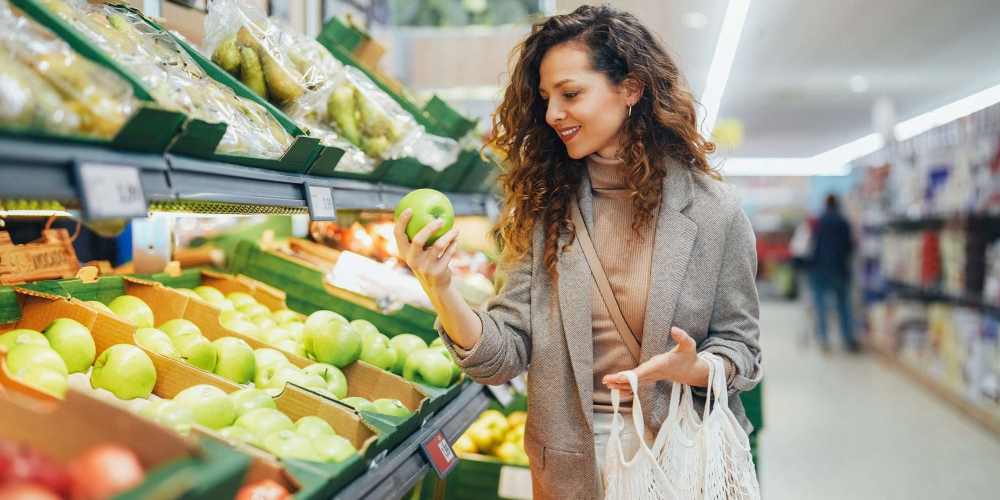 Woman shopping for apples at grocery store near The Mason in Augusta, Georgia