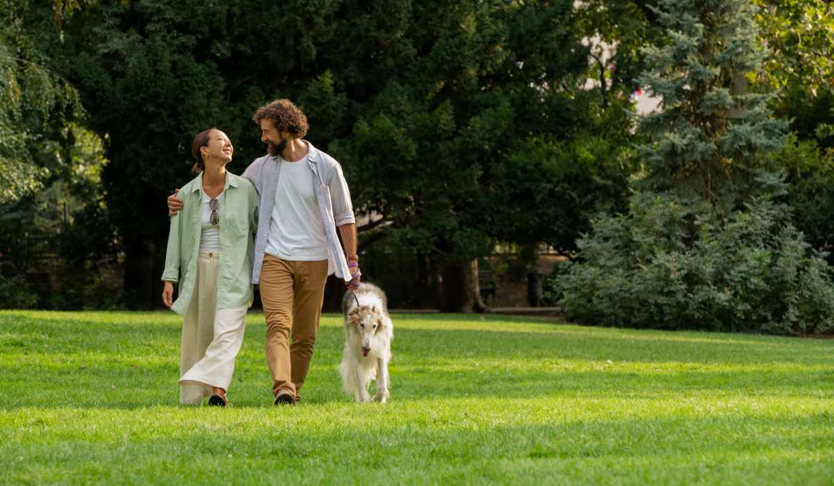 Couple walking a dog on green grass at Brixin Sonora in Fort Wayne, Indiana 