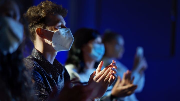 People wearing masks watching a theater performance