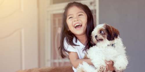 Resident child with her dog in living room at Ashgrove Farms Townhomes in Nicholasville, Kentucky