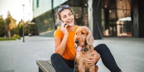 A woman sitting on a bench with her dog, both looking at a phone together at Kernwood Terrace in Los Angeles, California