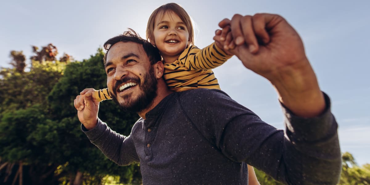 A father holding his daughter on his shoulders outside near Key Storage - Sonterra in San Antonio, Texas