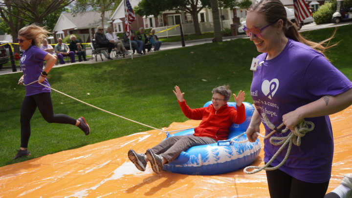 Touchmark resident riding innertube on a slip and slide