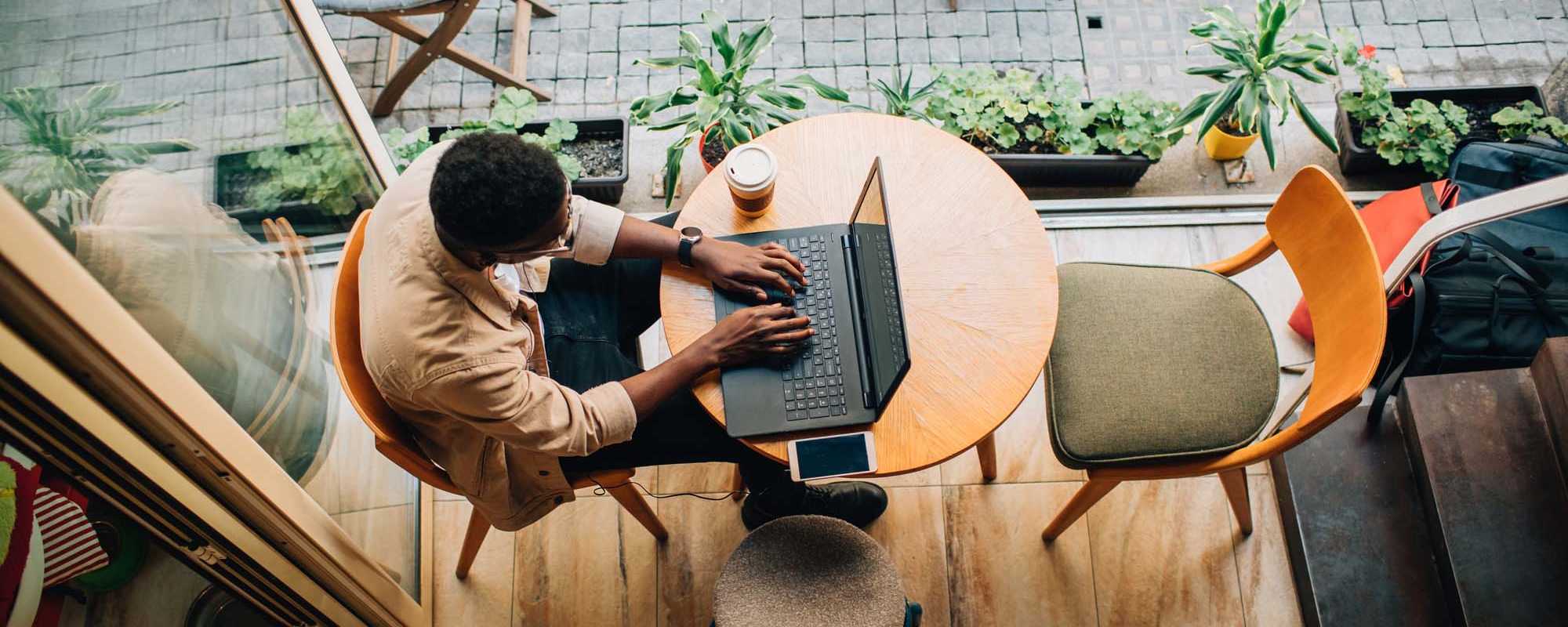 Contact Us | A man works on his laptop next to the window at The Lido Apartments in Los Angeles, California