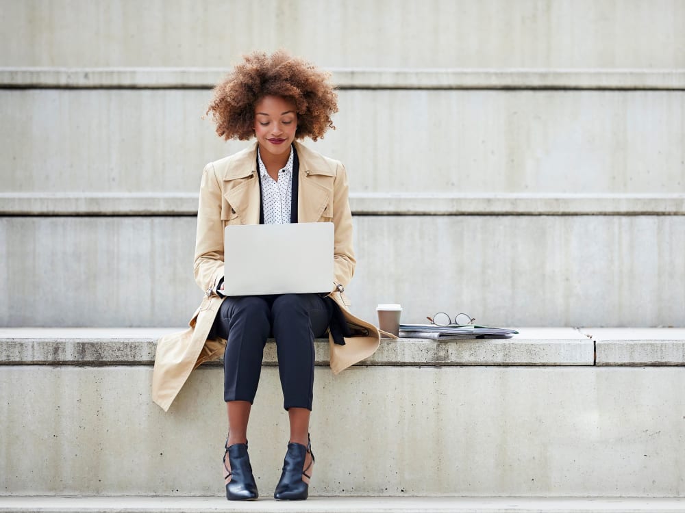 Resident sitting on some steps and working on her laptop near Alley South Lake Union in Seattle, Washington