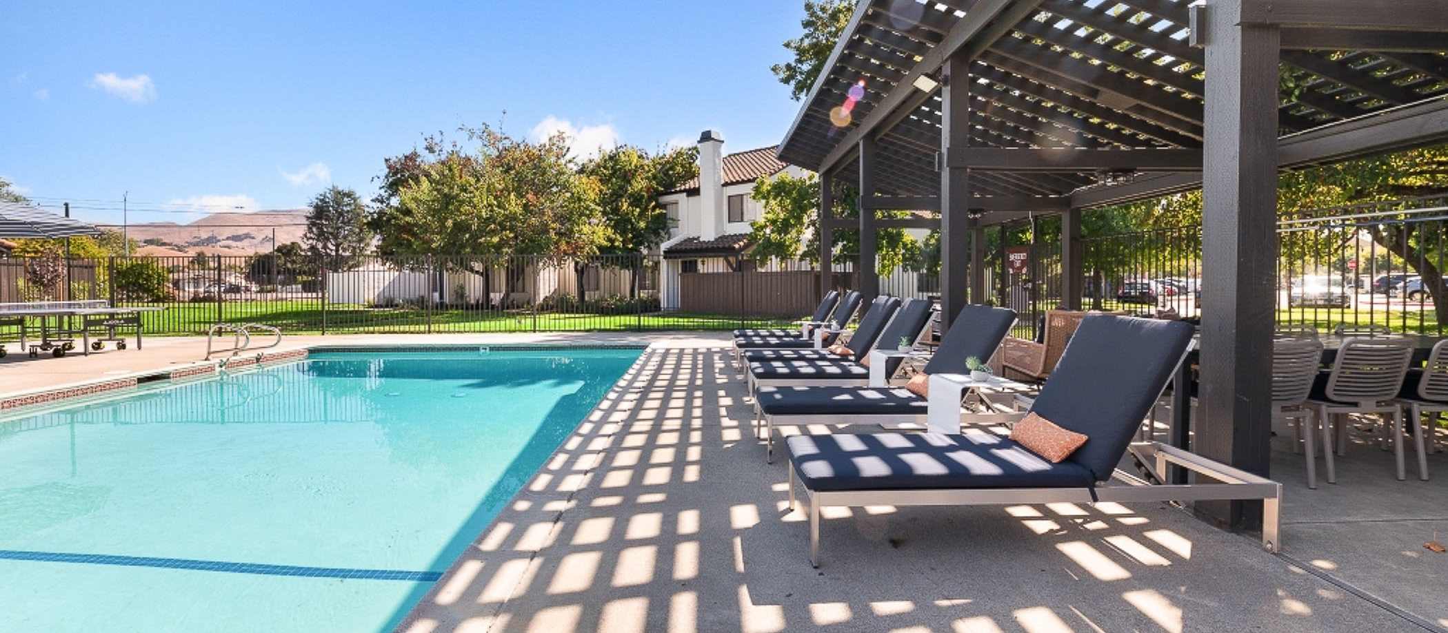 The pool at the park in the village, San Diego, California, surrounded by greenery and lounge chairs at Mariposa Fremont in Fremont, California