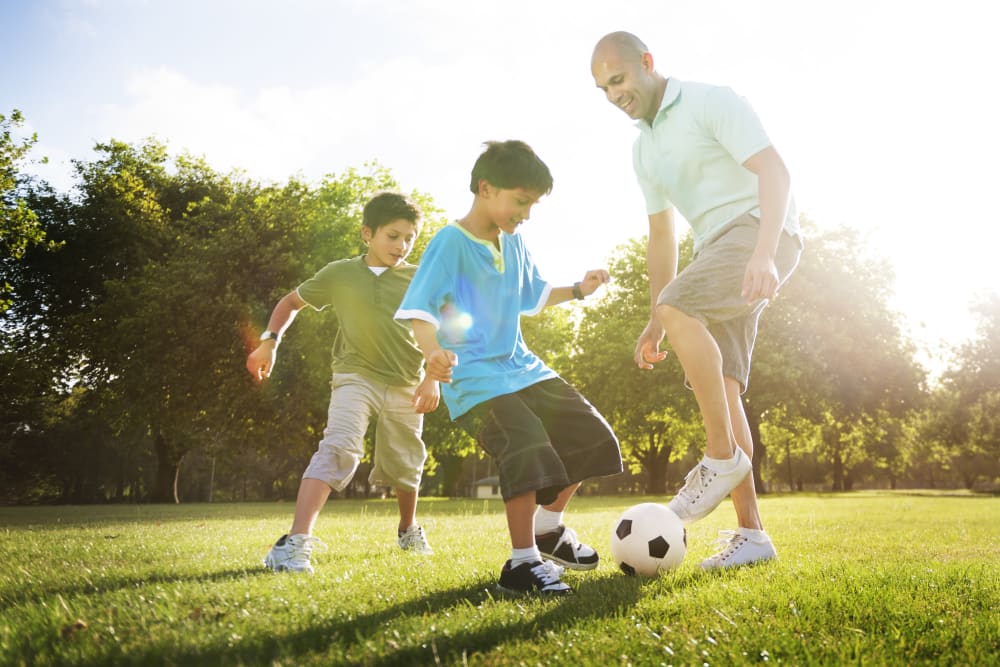Family playing soccer on the green grass at TerraLane at South Mountain in Phoenix, Arizona