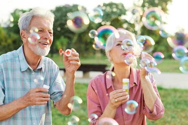 Senior couple laughing and blowing bubbles together outdoors at The Reserve at Round Rock.