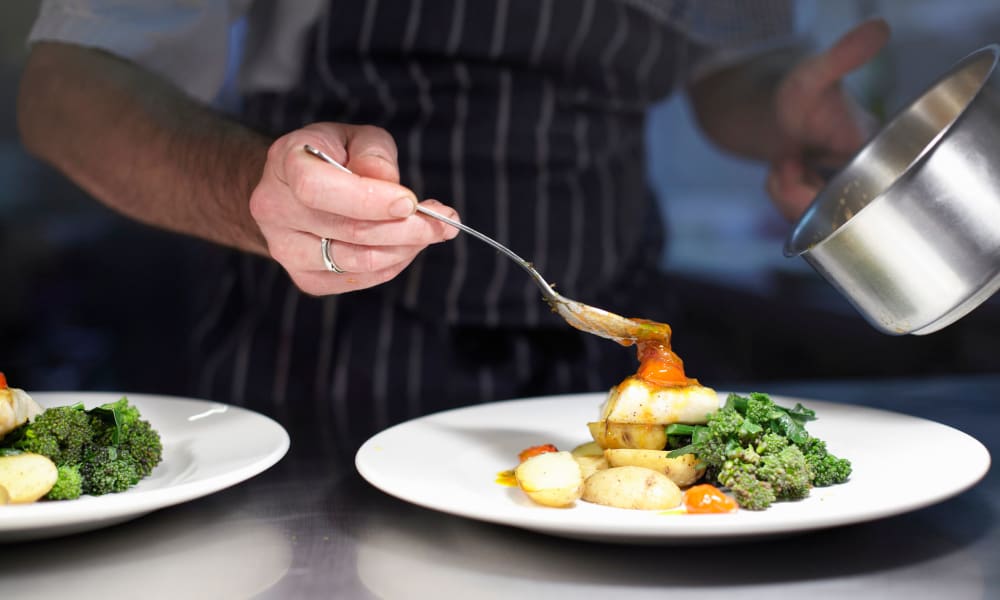 A chef garnishing a plate of food at Palo Alto Commons in Palo Alto, California