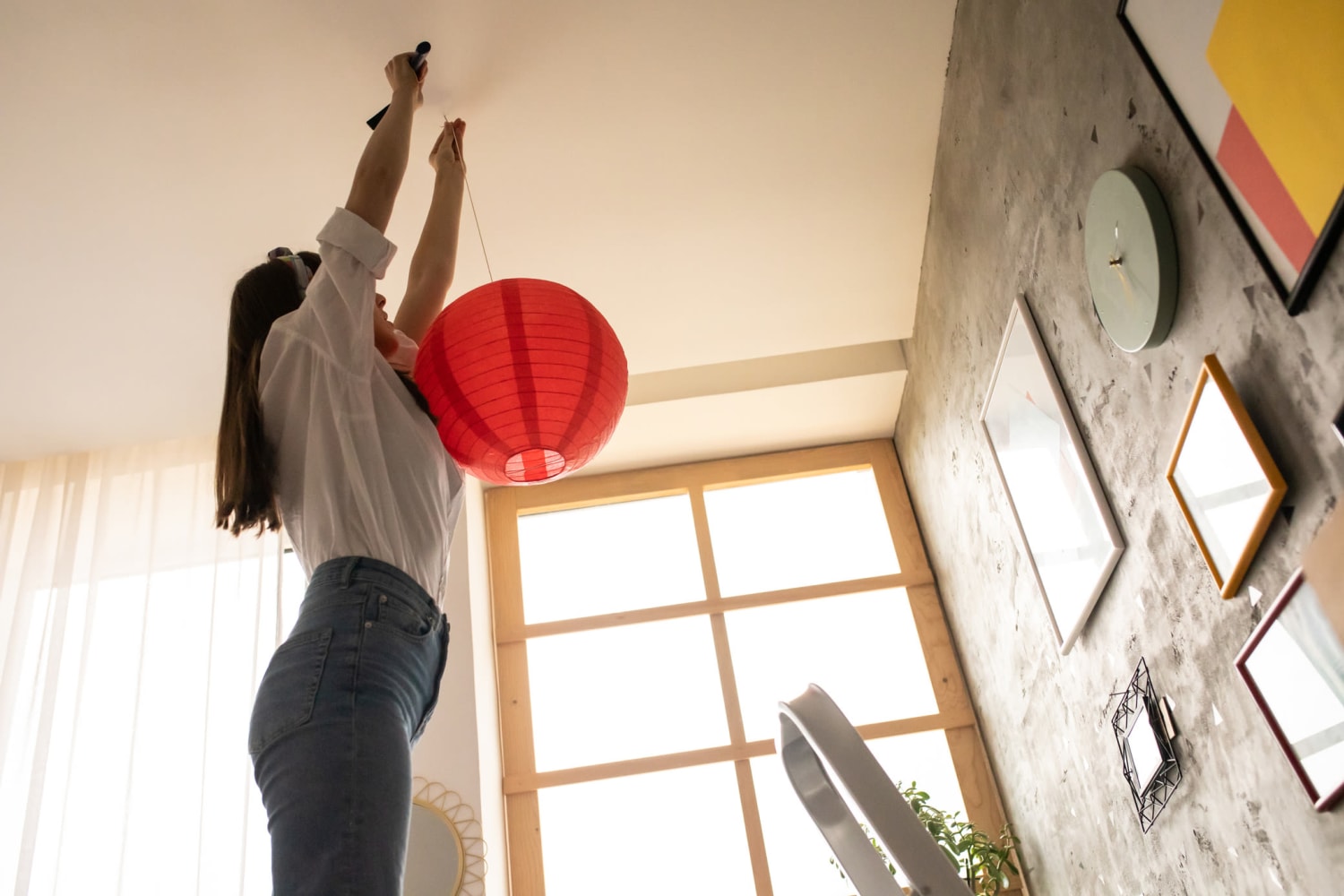 Woman hanging up some cool decorations in her home at Reserve at Castle Highlands Apartments in Castle Rock, Colorado