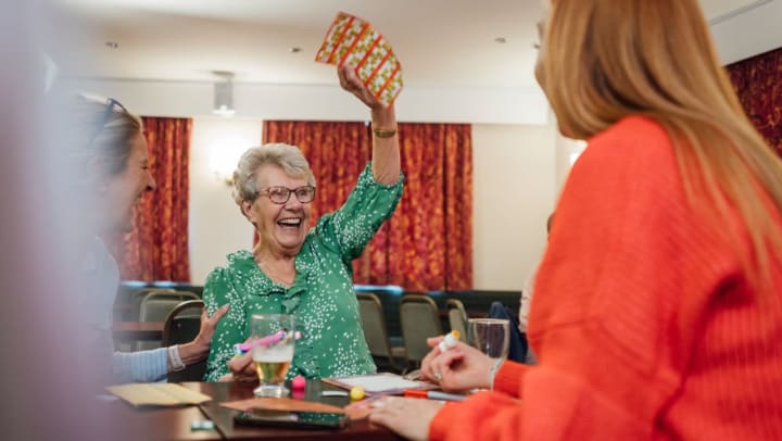 Senior woman smiling and holding up a winning bingo card 