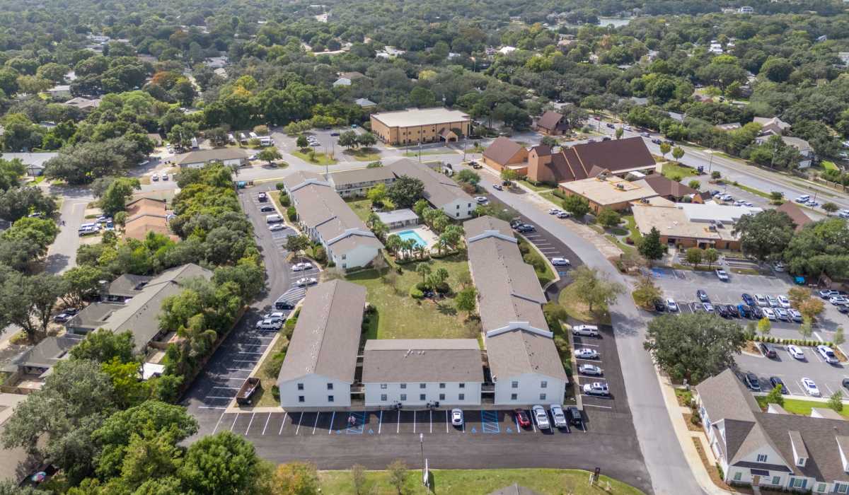 Aerial view of apartment community with pool and surrounding area at Breeze Apartments in Gulf Breeze, Florida
