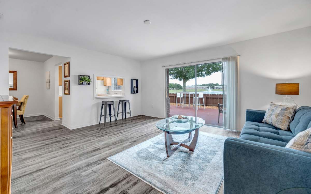Open layout living room with wood-style flooring and access to outdoor patio at Carlton Arms Of Winter Haven in Winter Haven, Florida