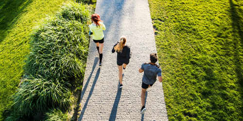 Three individuals jogging on a sunny pathway at a park near Reseda Village Green in Reseda, California