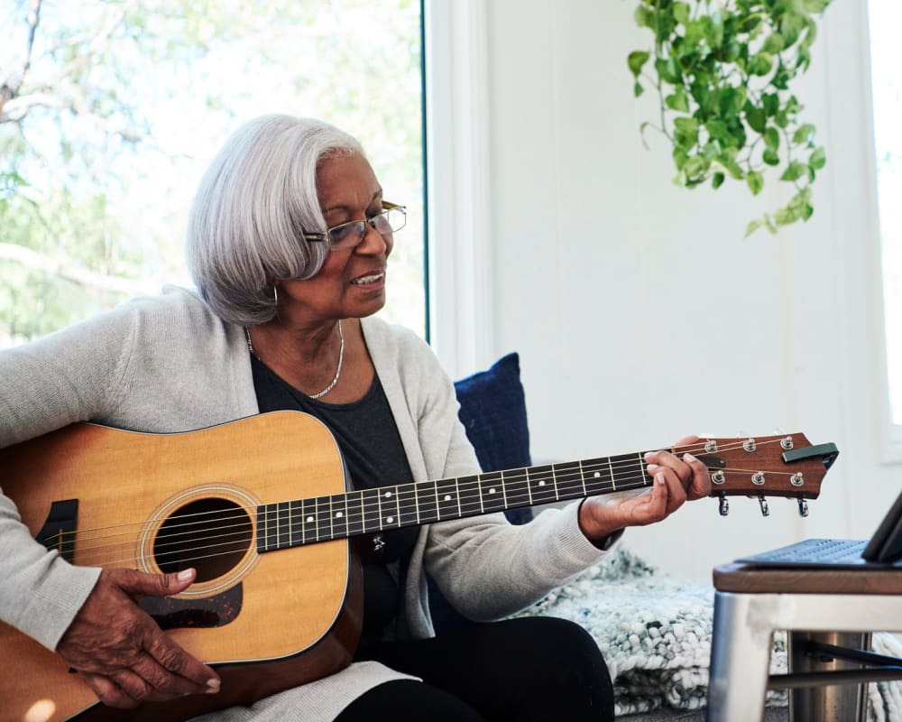 A resident learning to play guitar at The Peaks at Clinton Memory Care in Clinton, Utah