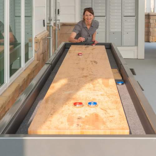 Resident woman playing shuffleboard at The Edison at Madison in Madison, Alabama