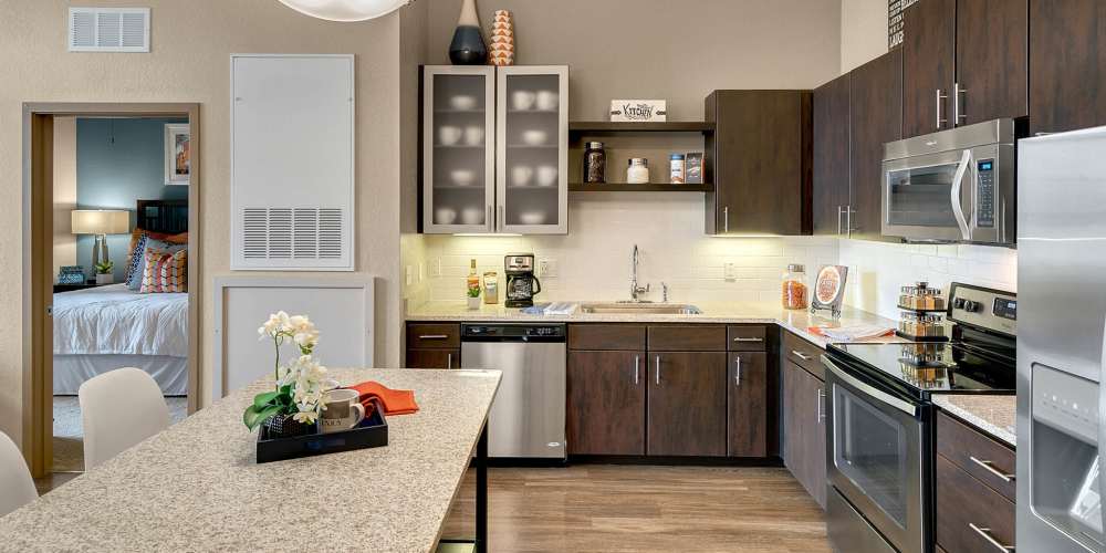 Apartment kitchen with dark wood cabinets and stainless steel appliances at Station House at Lake Mary in Lake Mary, Florida