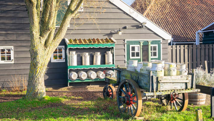 Wooden carts holding milk canisters next to barn at the New Mexico Farm and Ranch Heritage Museum.