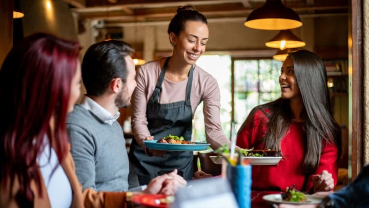 waitress serving food to a group of friends at a restaurant | restaurants in Ooltewah