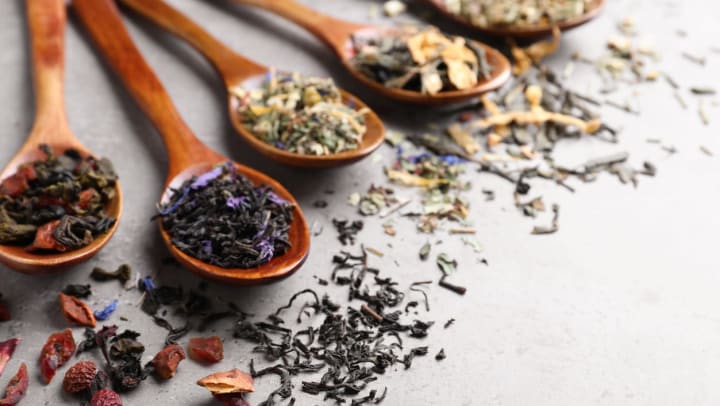 Various loose-leaf teas sitting on wooden spoons on a light gray stone table |  loose-leaf tea around Fort Worth