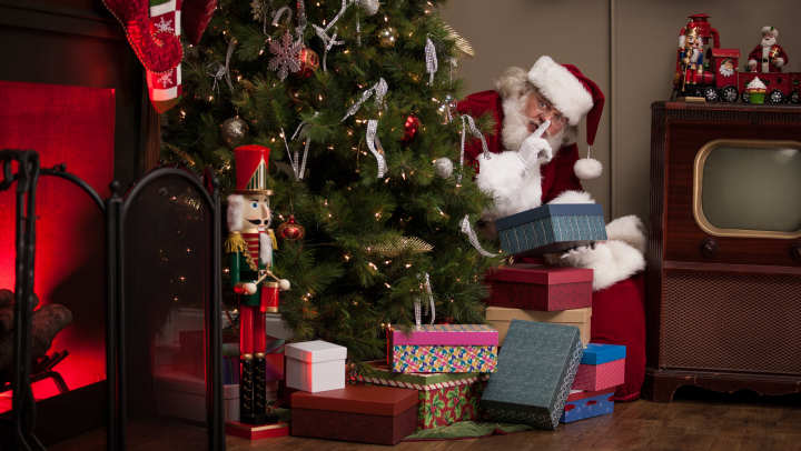 Santa sneakily putting presents under the tree