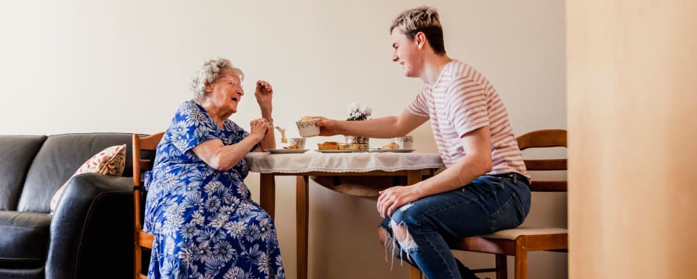 A young man eating with a resident at Flower Mound Assisted Living in Flower Mound, Texas
