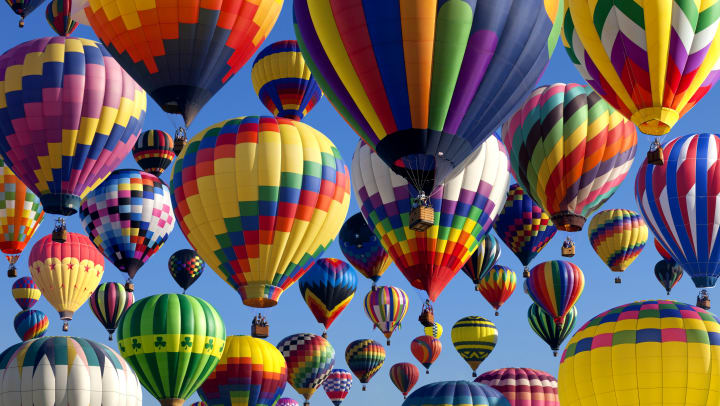 Many colorful hot air balloons in various patterns in the sky