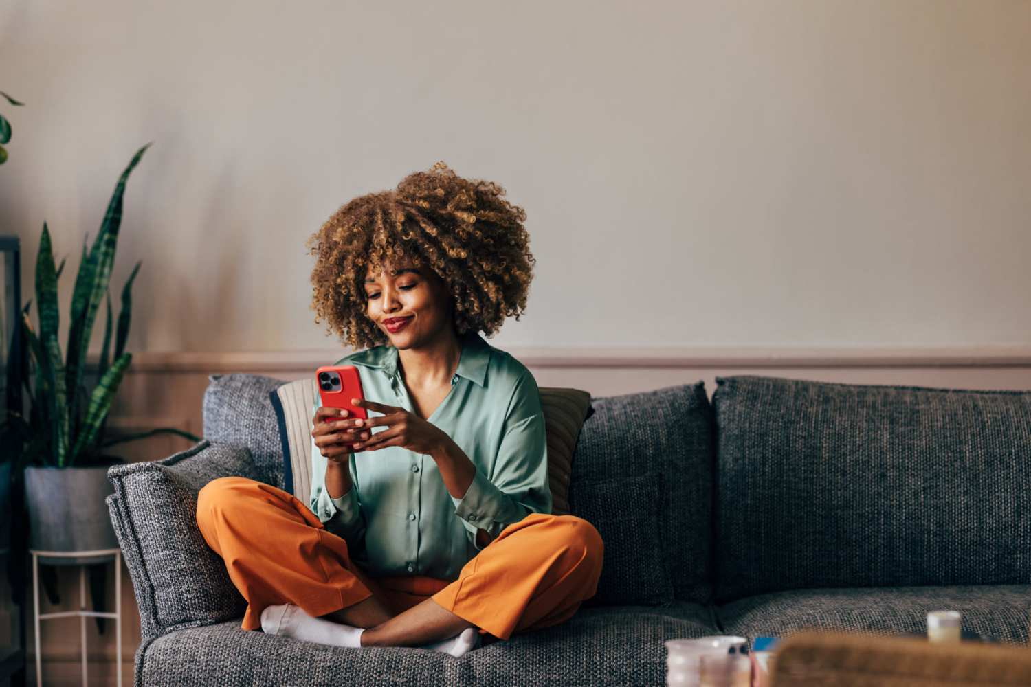 Resident using her mobile in her spacious living room at Knollview Apartments in Ovid, Michigan
