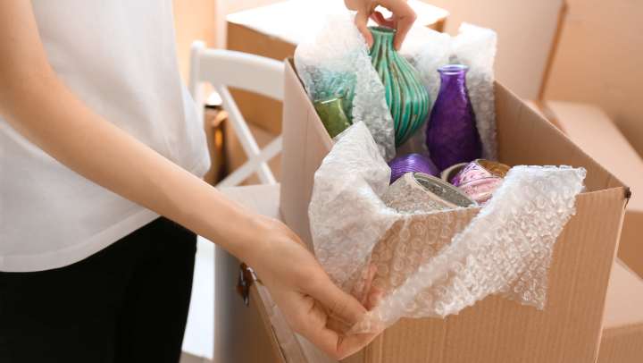 Woman packing fragile glassware in a box