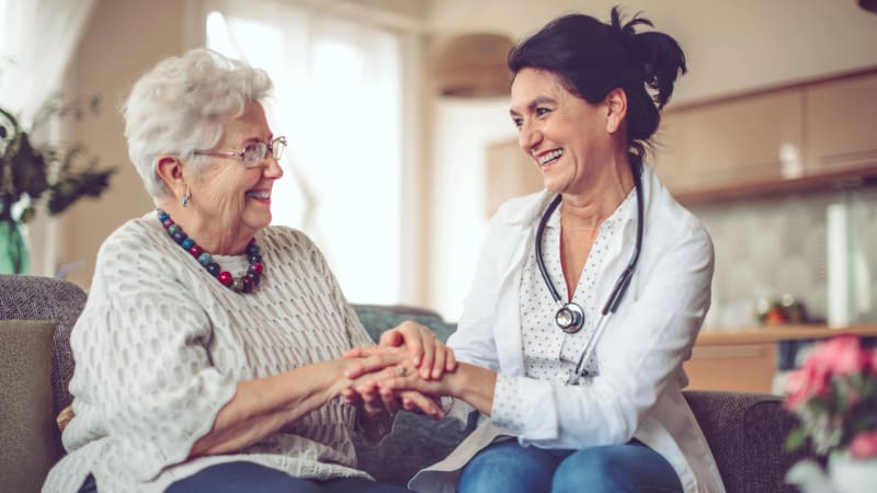 Nurse holding hands with smiling resident at Carriage Inn Conroe in Conroe, Texas