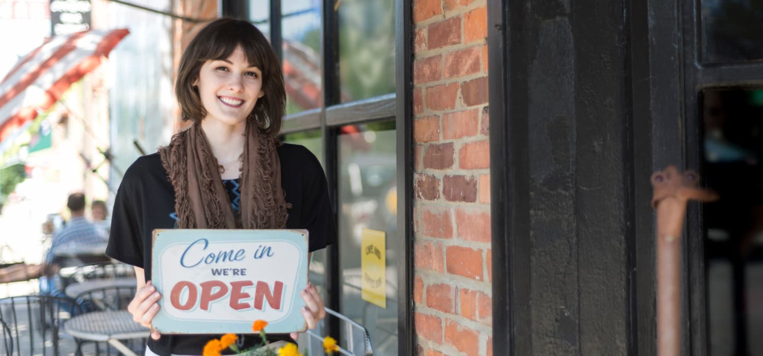 Woman with open sign in front of business in Chapel Hill , NC near Alta Blu