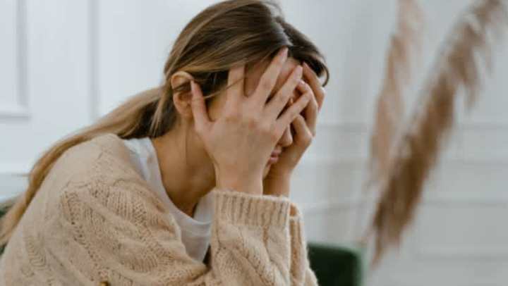 A woman buries her hands in stress.