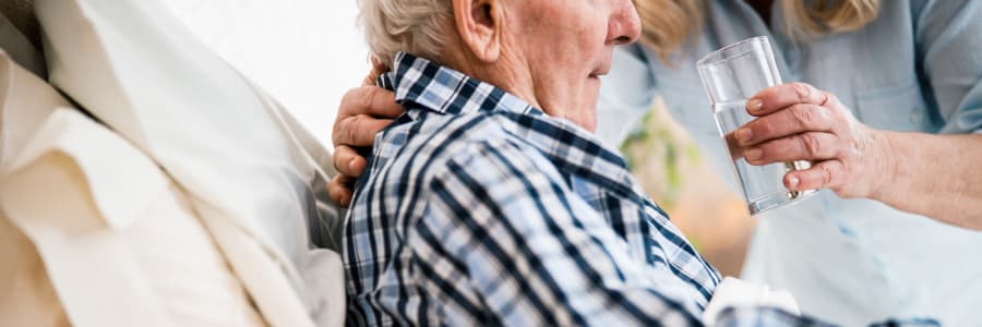 Resident in hospice care being given a drink of water by a caretaker at Retirement Ranch in Clovis, New Mexico