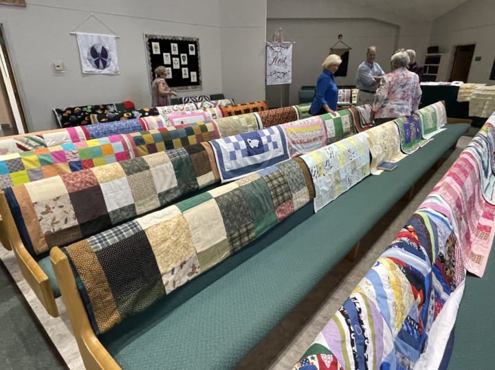 Quilts laid out on the pews of Trinity Lutheran Church for Blessing of the Quilts