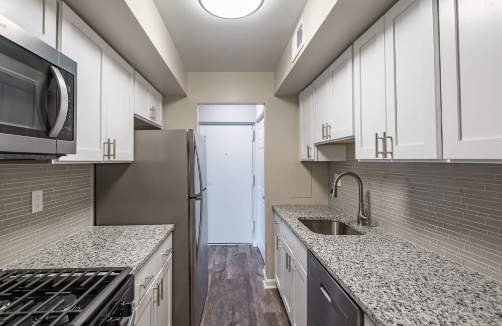 Kitchen with white cabinets, granite countertops, and stainless steel appliances at Village Square Apartments & Townhomes in Glen Burnie, Maryland