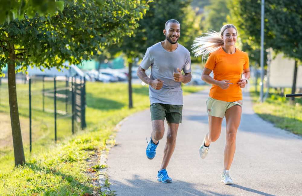 Resident couple jogging in a park surrounded by greenery near Reidy Creek Apartments in Escondido, California
