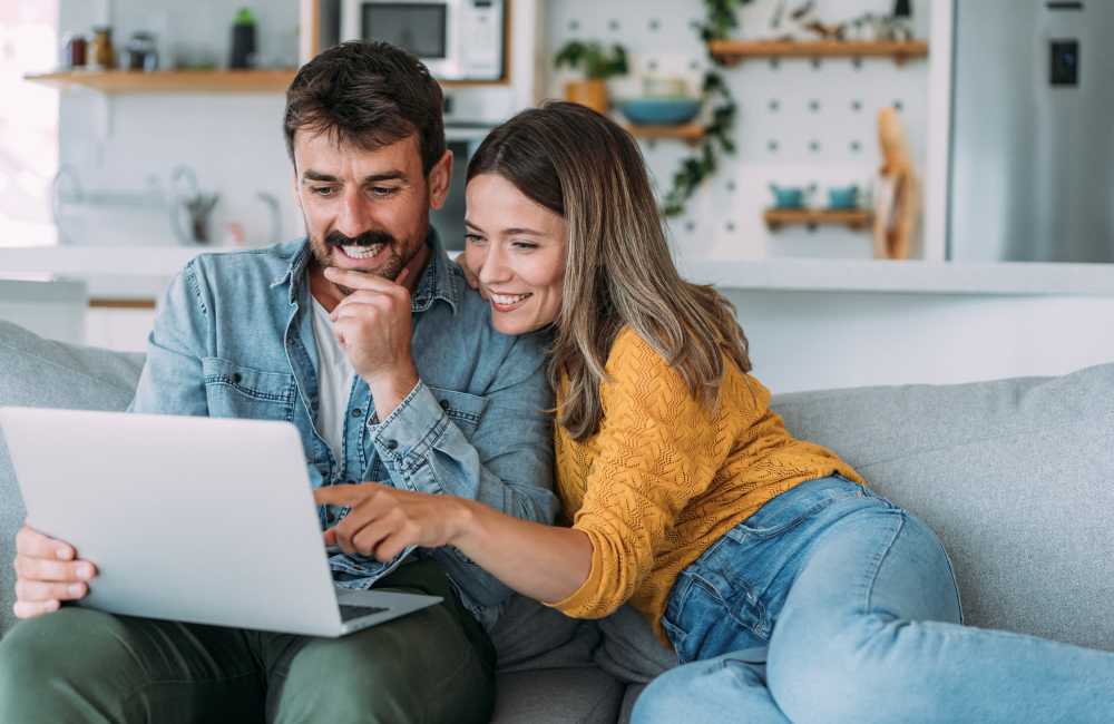 Couple in their home looking at a laptop at Mountain Breeze Villas in San Bernardino, California