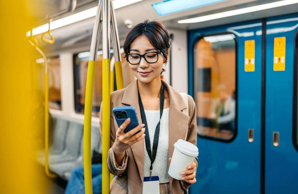 Commuter enjoying coffee while using phone in subway train at Trolley Court in San Diego, California 