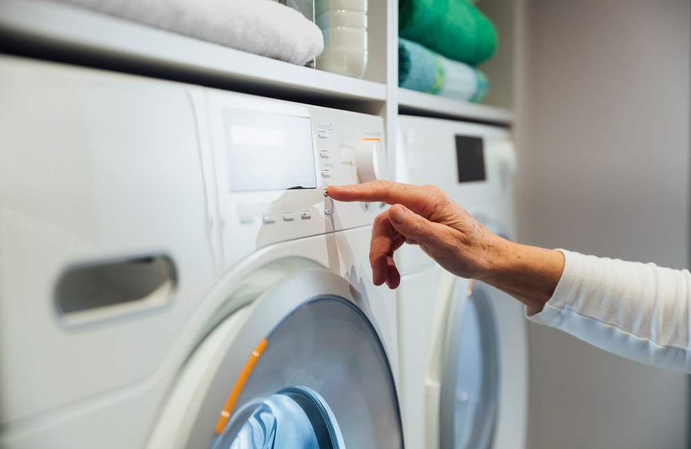 Resident using washing machne in her home at Lancer Commons in Lancaster, South Carolina