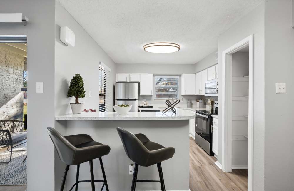Kitchen with a breakfast counter with white granite countertop and two chairs at 18Eleven Frankford in Carrollton,Texas
