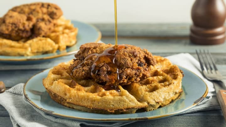 A close-up of syrup being poured on a plate of chicken and waffles at a Gilbert restaurant