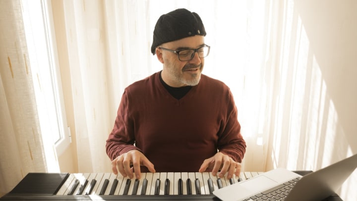 man playing a piano while looking at a laptop | Flagstaff music schools