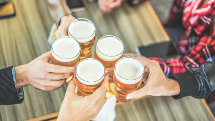 Close up of group of friends cheering beers at a bar | Bars in Sarasota