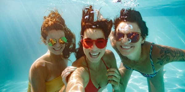 Friends posing for a photo underwater in the resort-style pool at The Vic in Greensboro, North Carolina