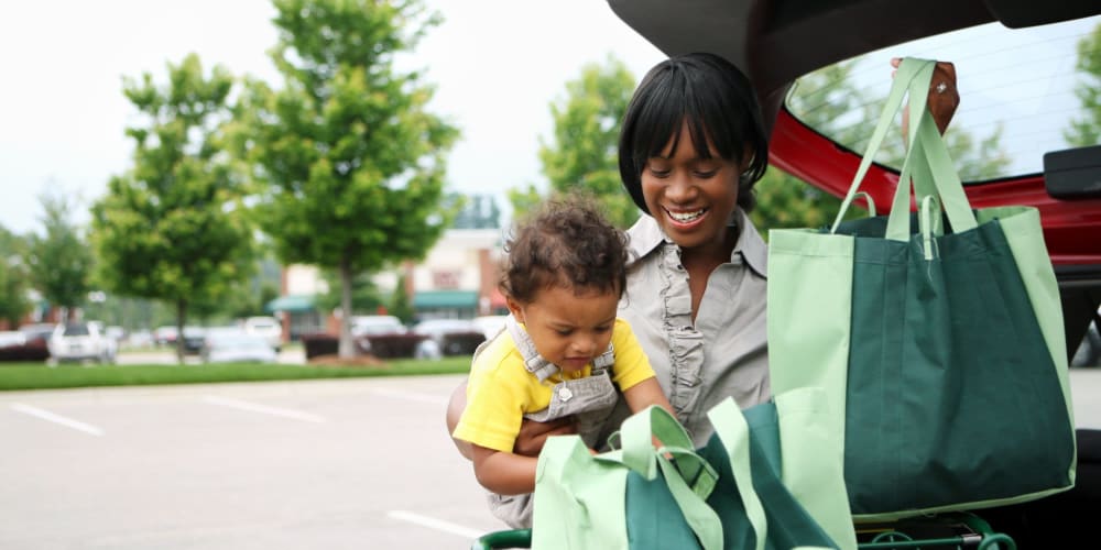 Woman holding a child and loading groceries into her trunk near Coronado Springs East in Palm Springs, Florida