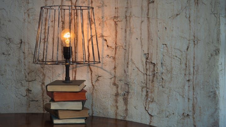 Lamp made from a stack of books and a bulb with iron shade.