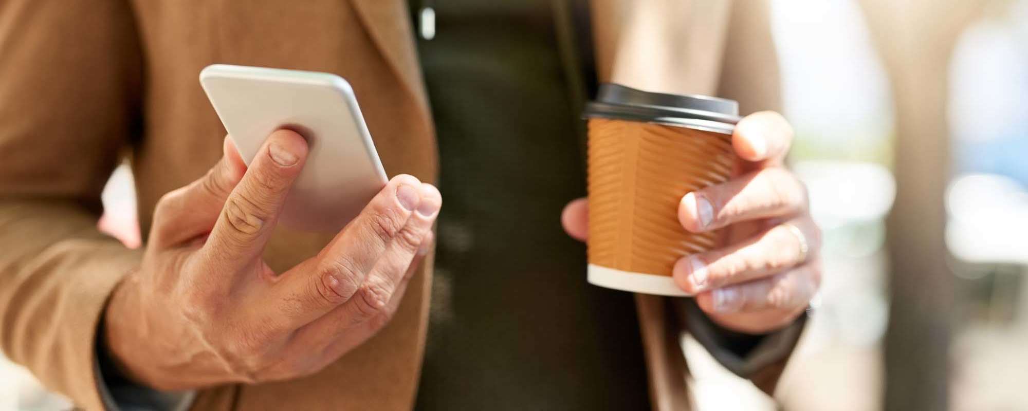 Contact Us | A man in a blazer holding his phone and a coffee cup at Tides on Tropicana in Las Vegas, Nevada