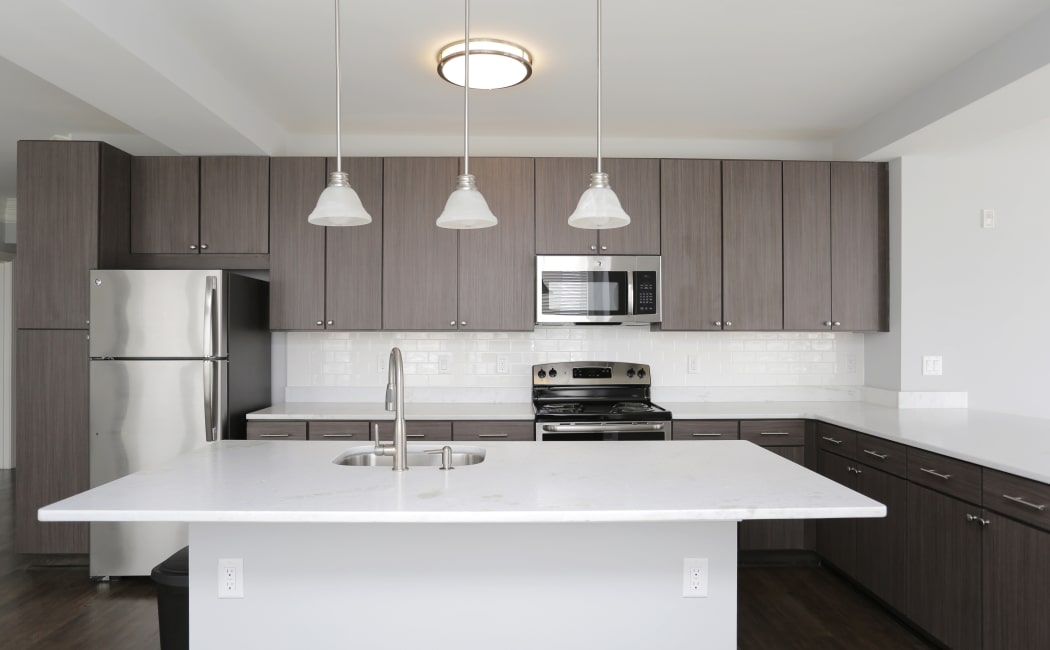 Modern kitchen with stainless-steel appliances and subway-tile backsplash in model home at Aqua on 25th in Virginia Beach, VA